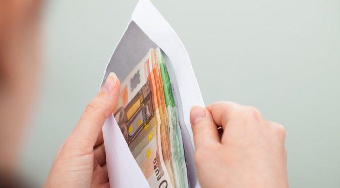 CUSTO DE VIDA E MÉDIA DE SALÁRIO NA IRLANDA Mãos segurando um envelope cheio de euros. Custo de vida e média de salário na Irlanda